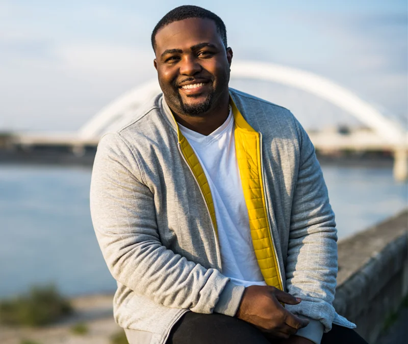 Large sized man posing on the side of a bridge